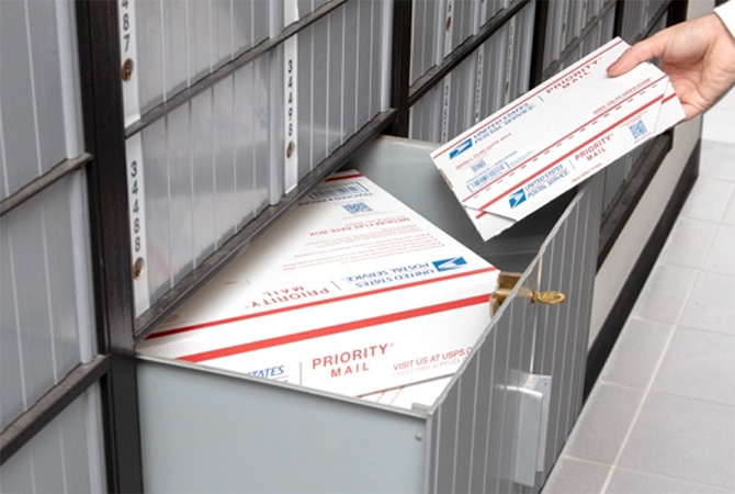A person getting their Priority Mail packages out of a large PO Box.